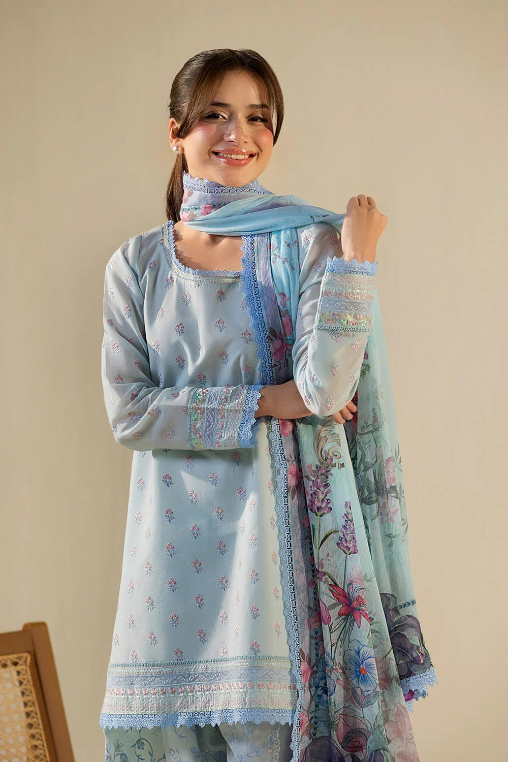Woman wearing a light blue embroidered dress with a matching dupatta against a beige background