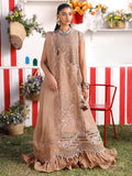 Woman in a beige embroidered dress standing outdoors with a colorful background
