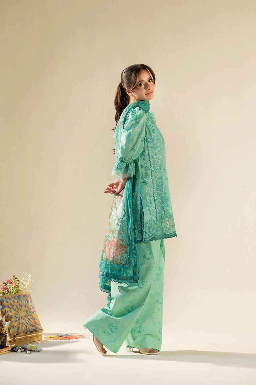 Woman wearing a light green traditional outfit with a beige background