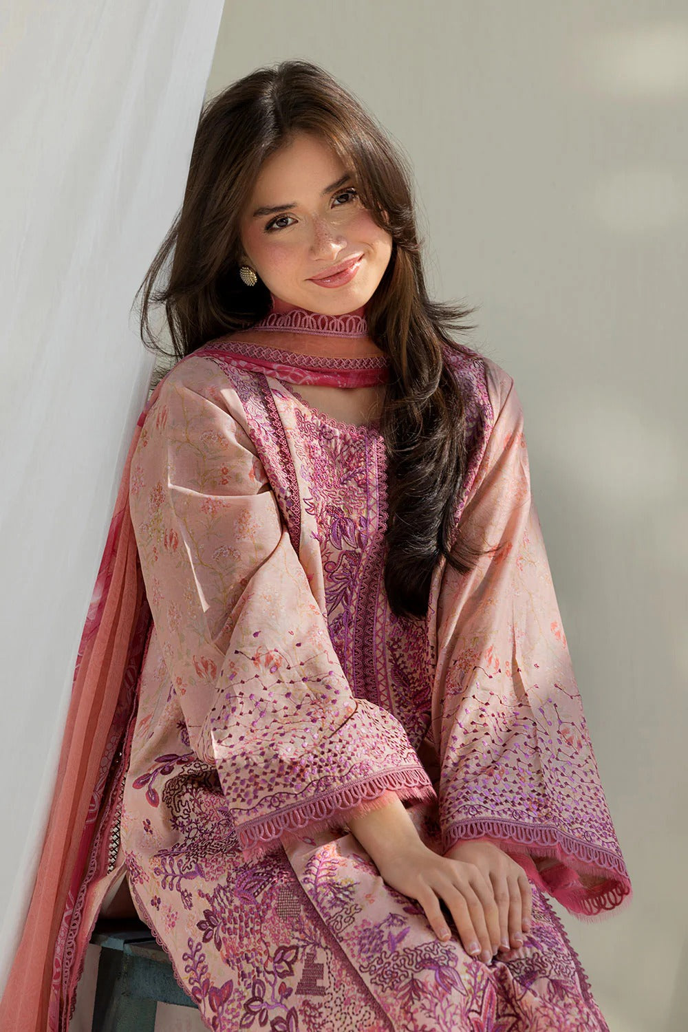 Woman wearing a pink and purple traditional outfit with a matching shawl against a white background