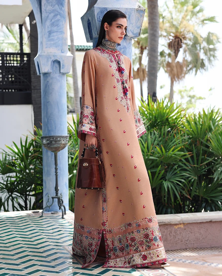 A woman models a beige long-sleeve embroidered kurta with floral patterns on the hem and cuffs, styled with a brown handbag in an outdoor courtyard setting.