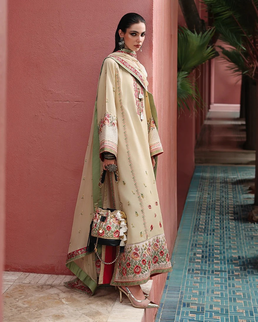 A woman models a traditional South Asian outfit consisting of a beige embroidered kurta, a green dupatta, and a matching embroidered handbag, set against a pink wall and blue tiled floor.