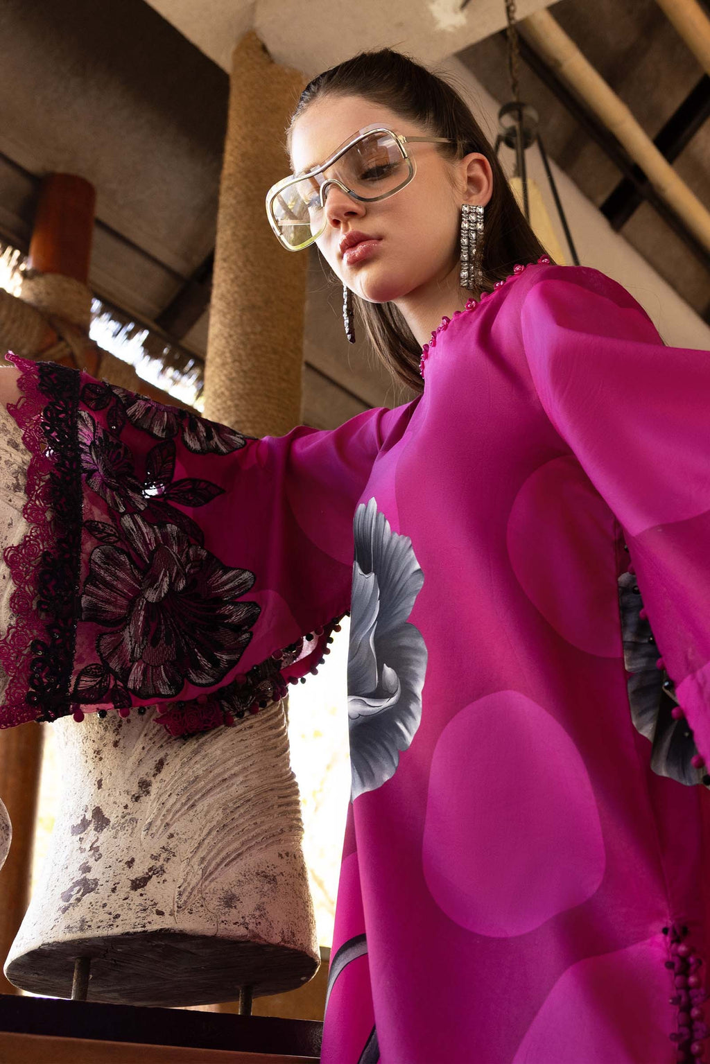 Woman wearing a bright pink outfit with floral patterns indoors.