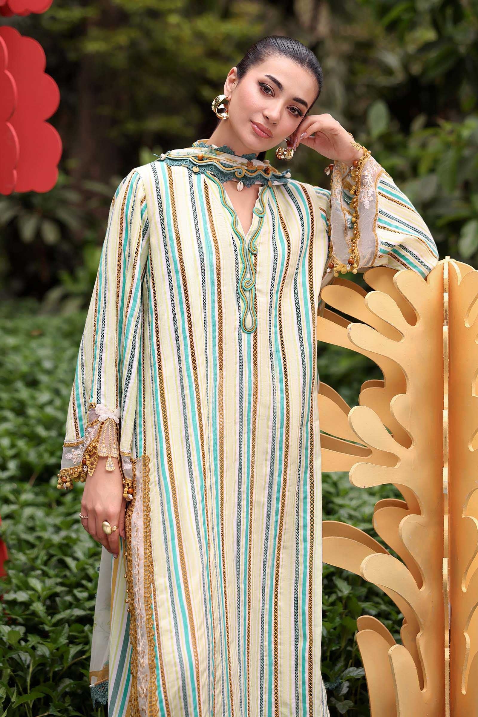 Woman in a striped dress standing outdoors with greenery in the background
