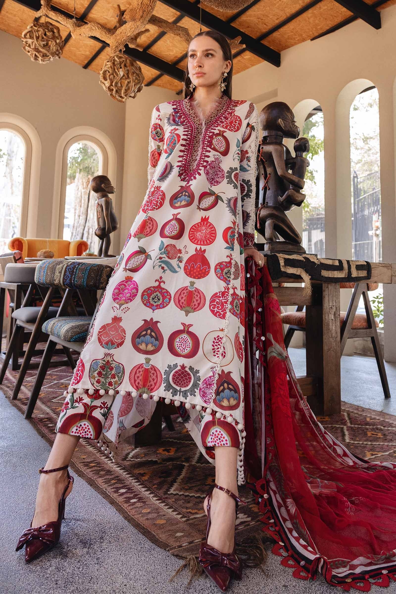 Woman in a traditional embroidered dress with a red dupatta in an indoor setting.