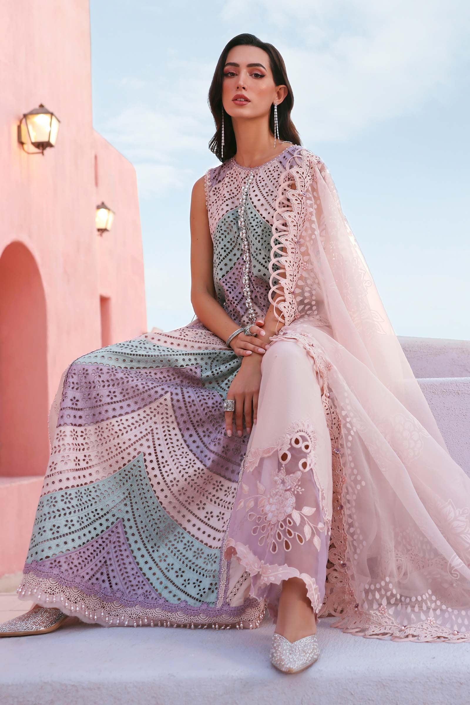 Woman in a colorful dress with a pink building and blue sky in the background