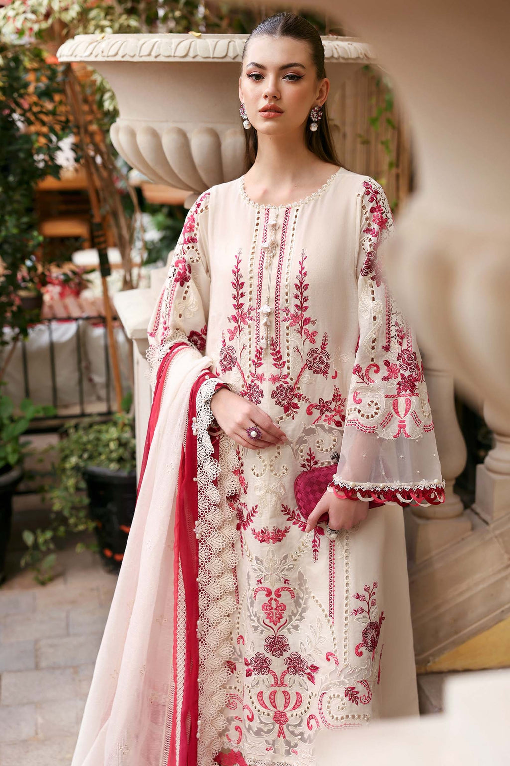 Woman wearing a cream and pink embroidered traditional outfit with a red dupatta.