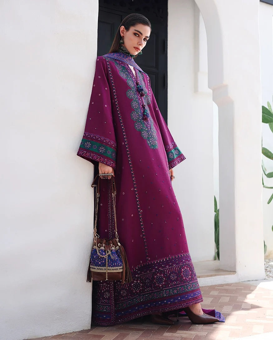 A woman models a traditional deep purple embroidered kurta set with a matching handbag, standing in a white-walled architectural setting.