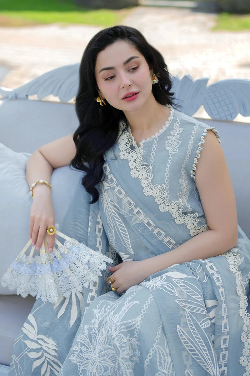 Woman in a light blue dress with white lace details sitting outdoors.