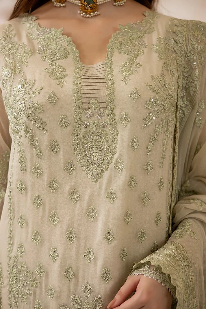 Close-up of a beige traditional embroidered outfit with intricate silver and green sequin work, featuring a deep V-neckline and detailed sleeve embroidery.