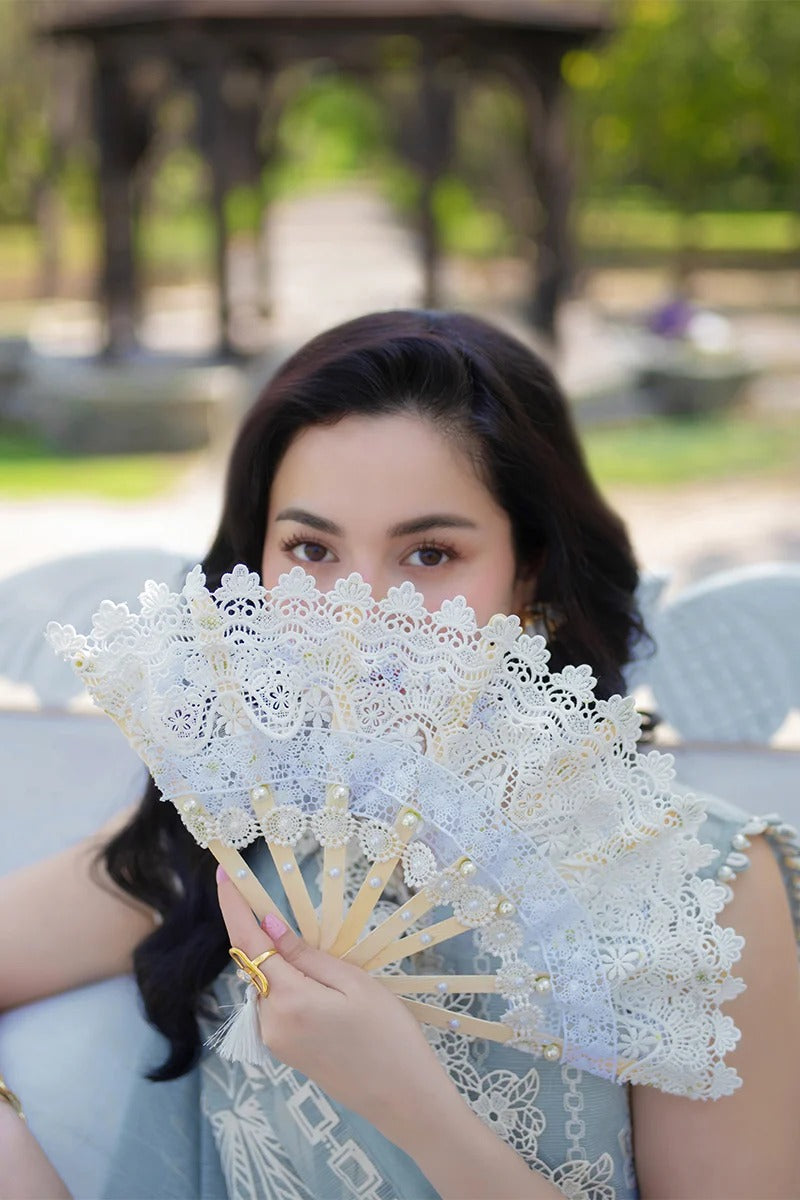 Woman holding a lace fan outdoors with blurred background