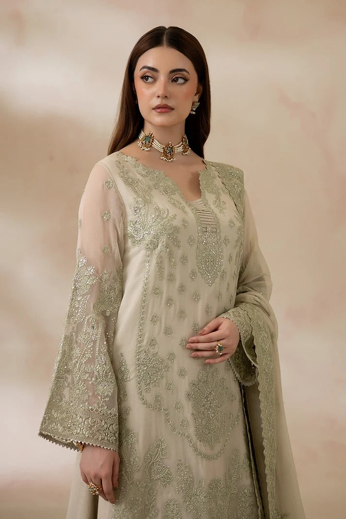 A woman models a traditional South Asian outfit featuring a beige kurta with intricate olive green embroidery, paired with a matching sheer dupatta and a coordinating green choker necklace.