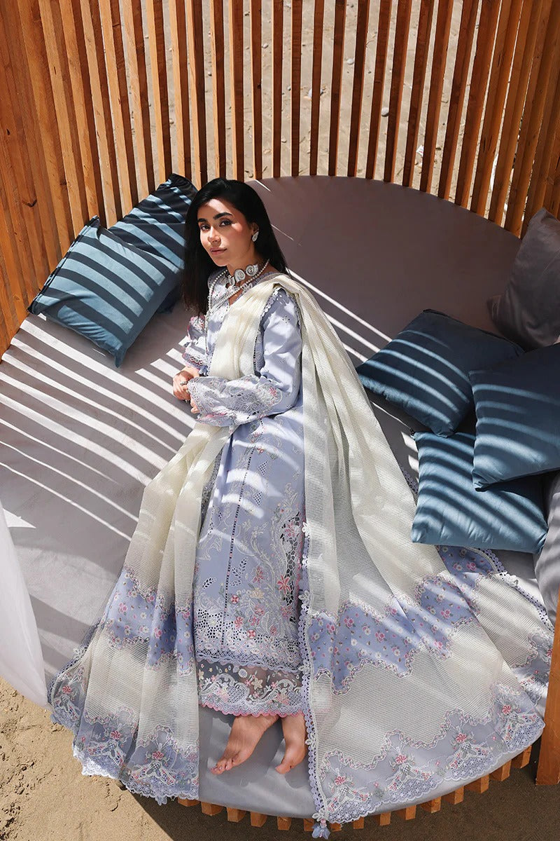 Woman in a traditional outfit sitting on a wooden bench with striped cushions.