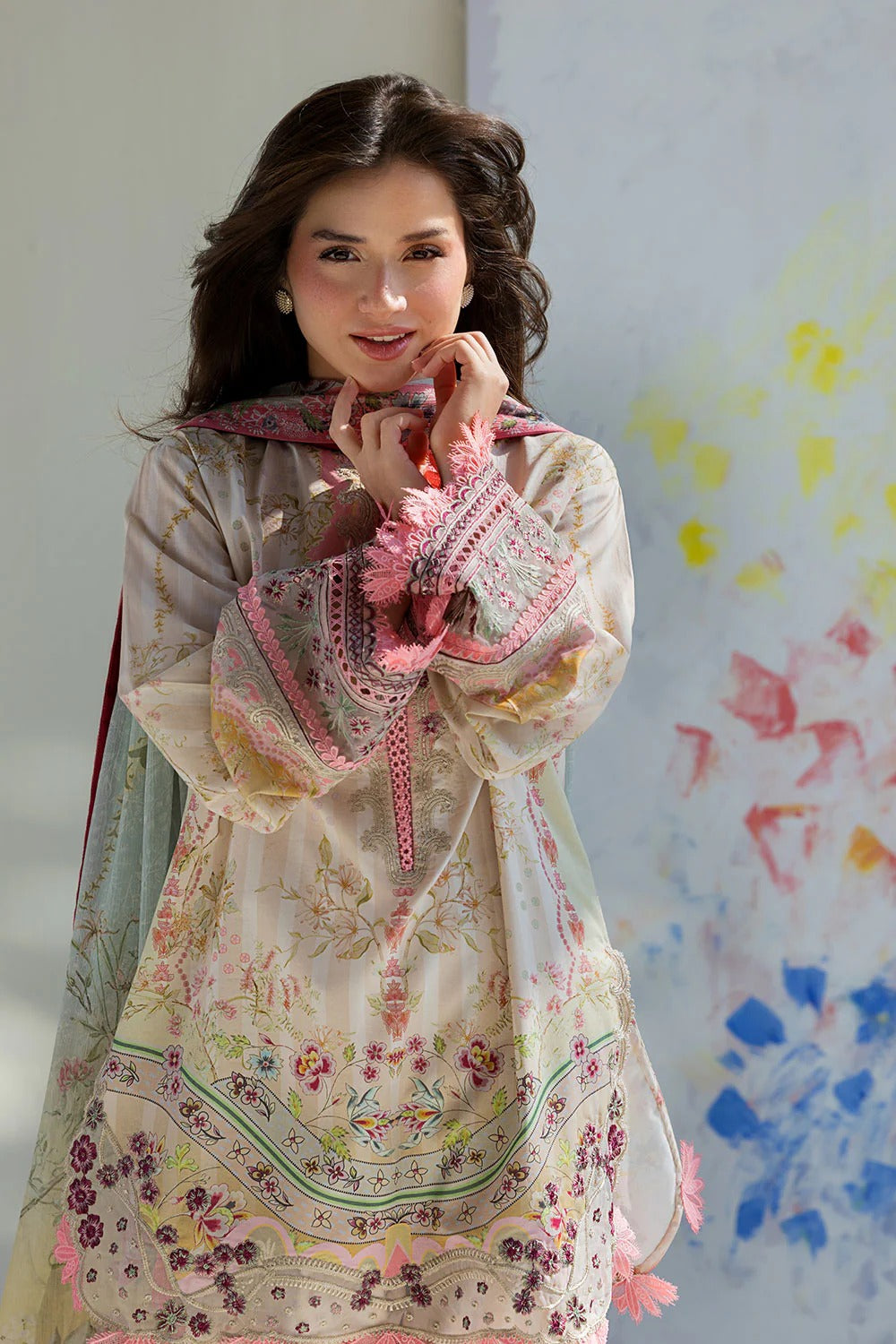 Woman wearing a traditional embroidered dress with a colorful abstract painting in the background