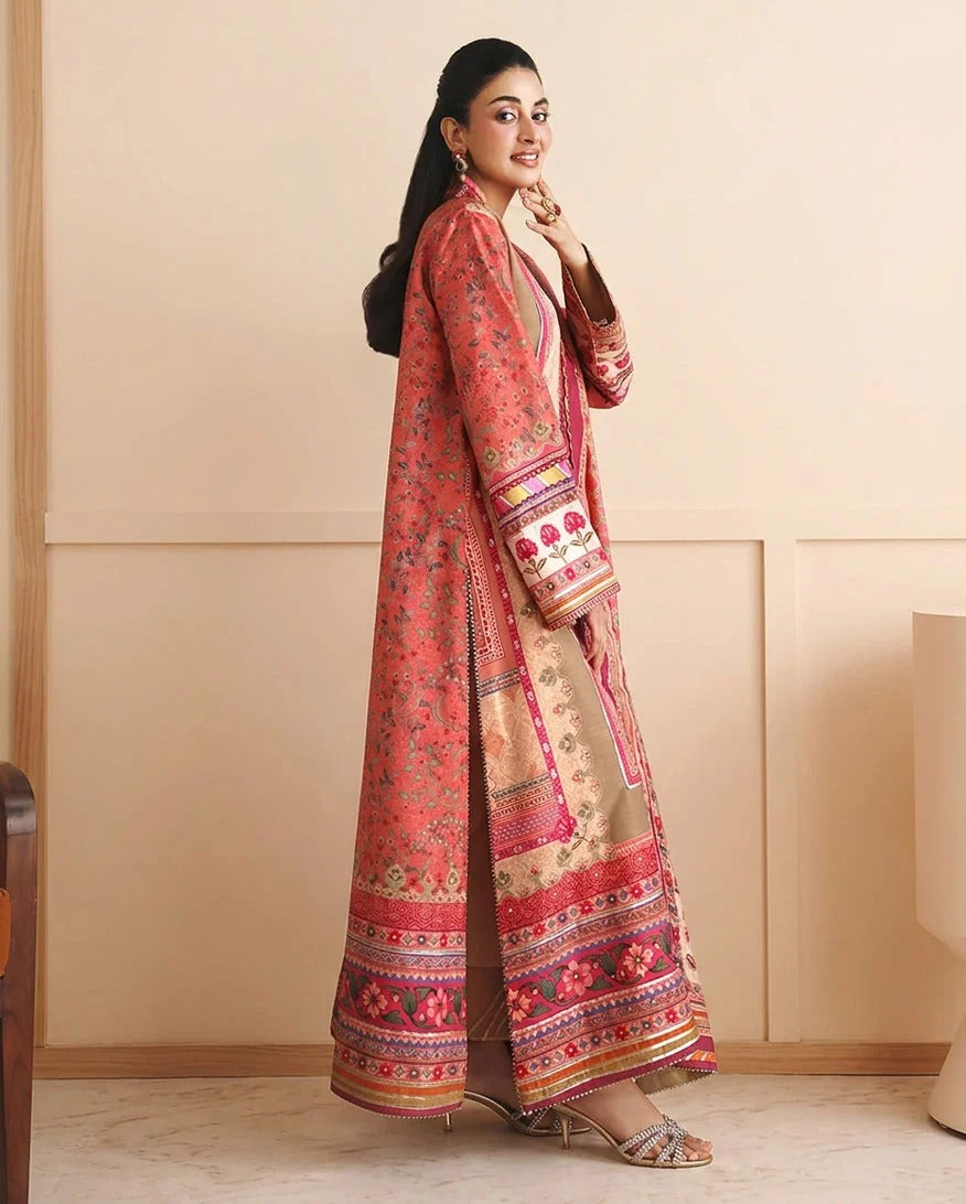 A woman models a traditional long pink and beige embroidered kurta set with a matching embroidered shawl, standing in a beige paneled room.