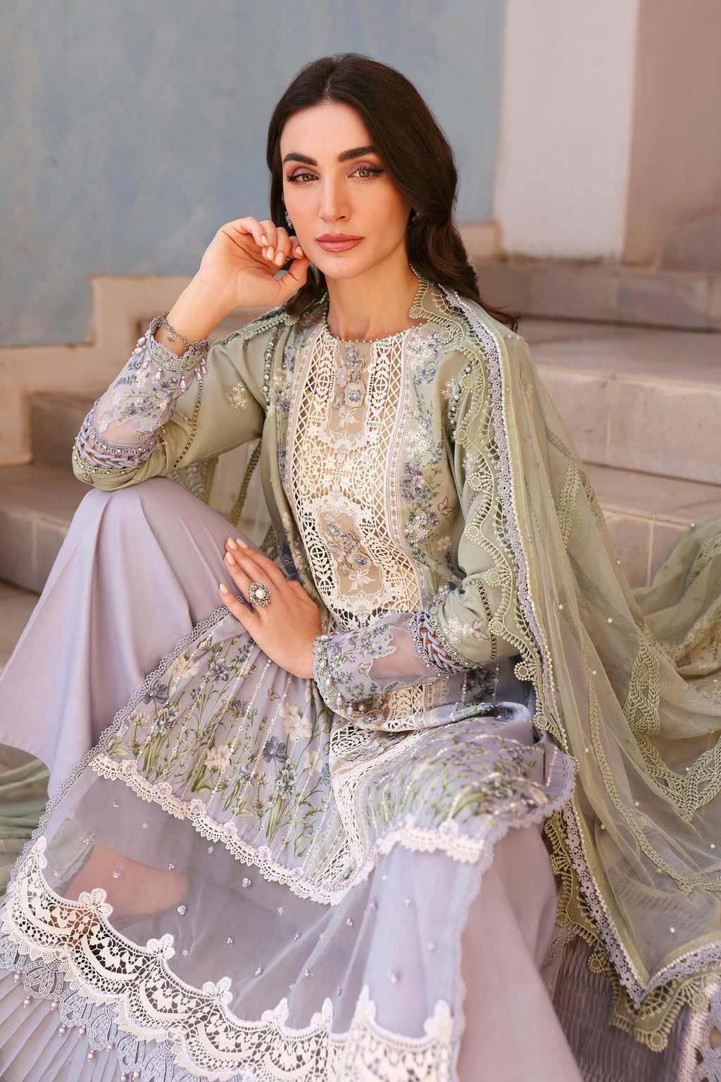 Woman in traditional embroidered outfit sitting on steps with a blurred background