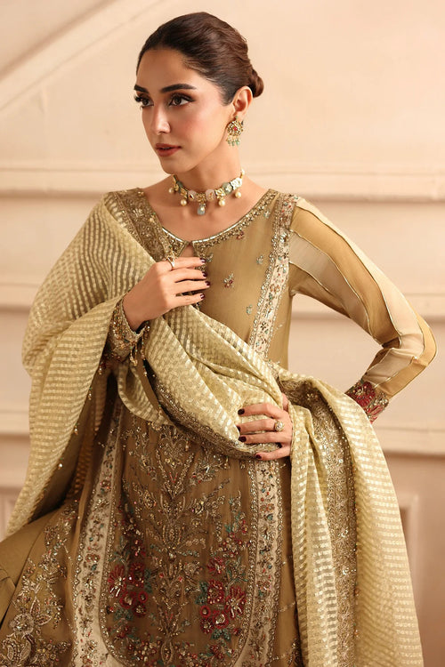 A woman models a traditional South Asian ensemble featuring a beige and gold embroidered kurta with a matching patterned dupatta, set against a soft beige architectural background.
