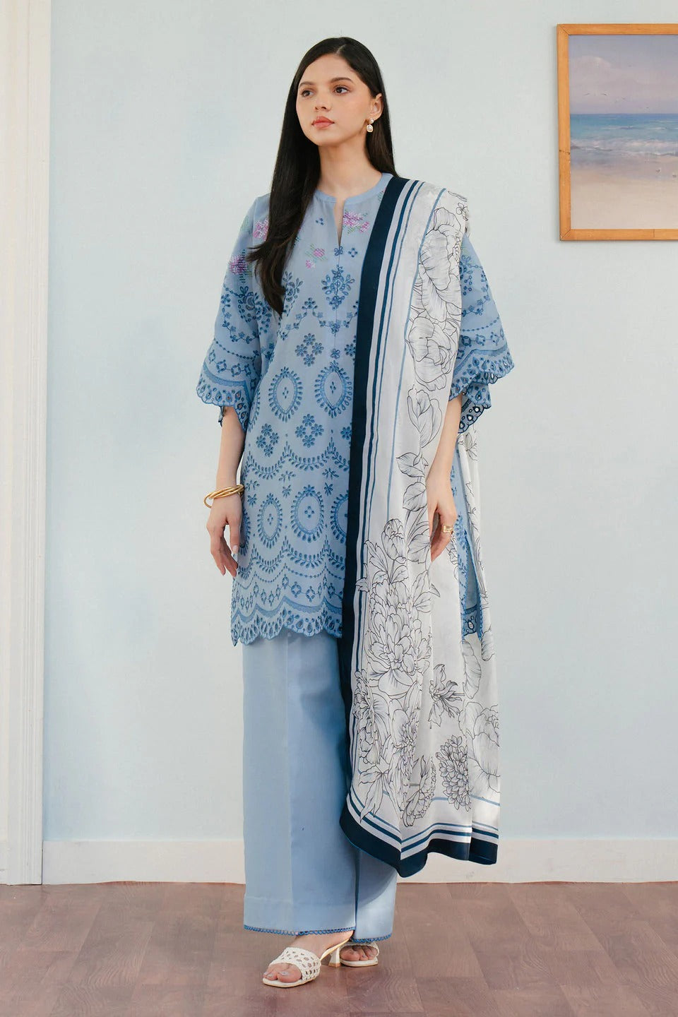 Woman wearing a blue and white traditional outfit with a matching dupatta in a room.