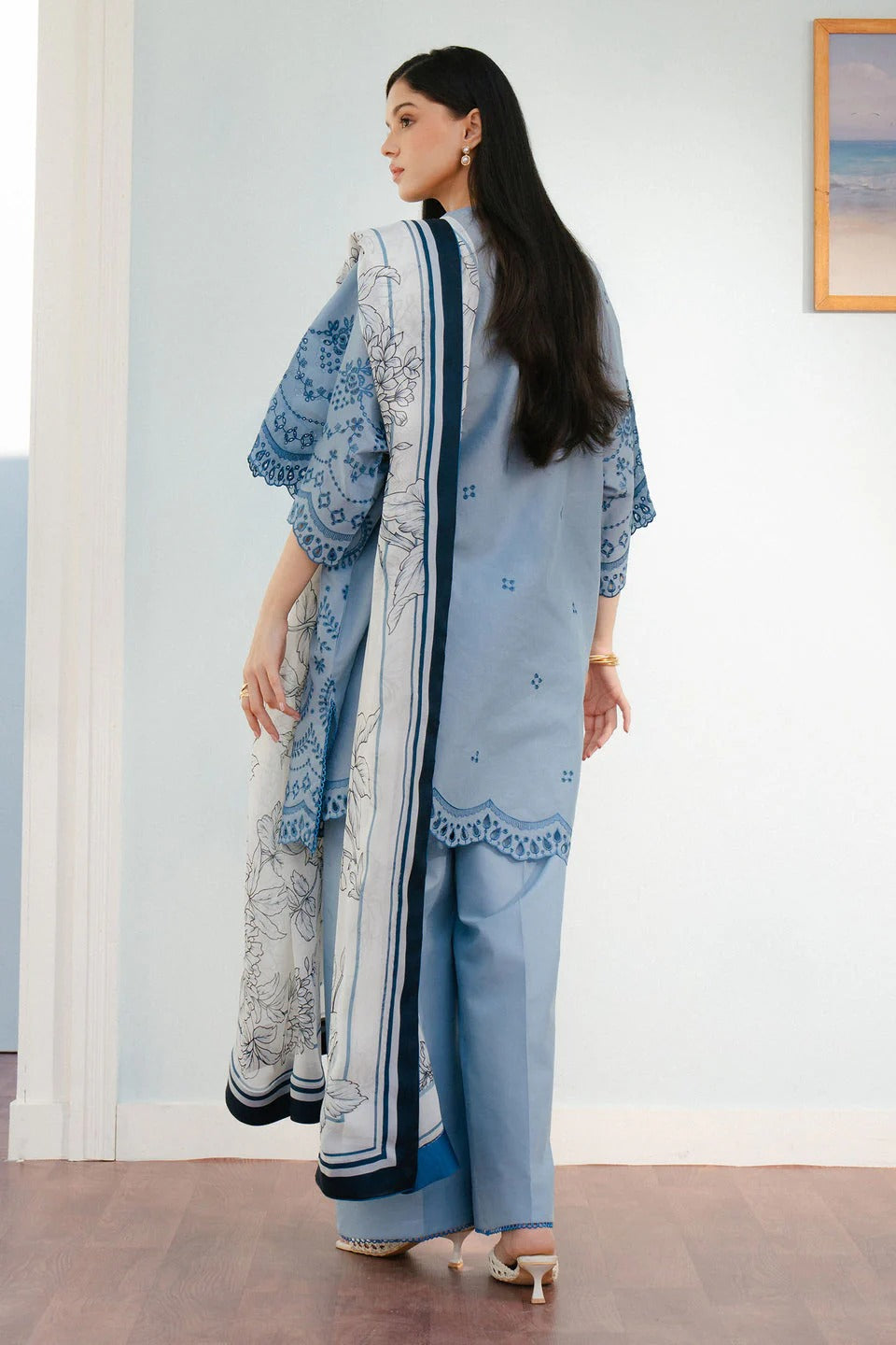 Woman wearing a light blue traditional outfit with a matching dupatta in a room.