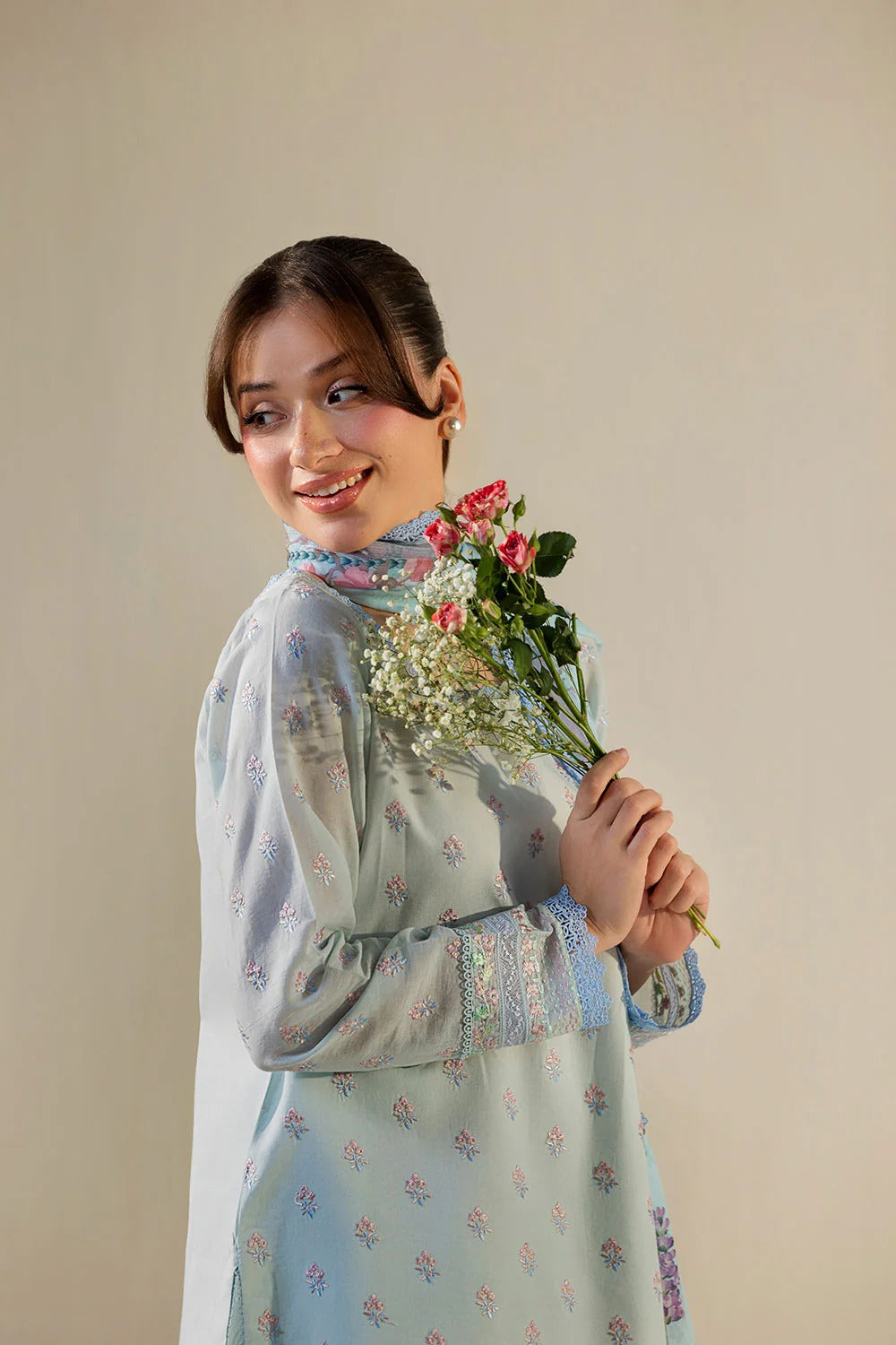 Woman holding a bouquet of flowers against a plain background