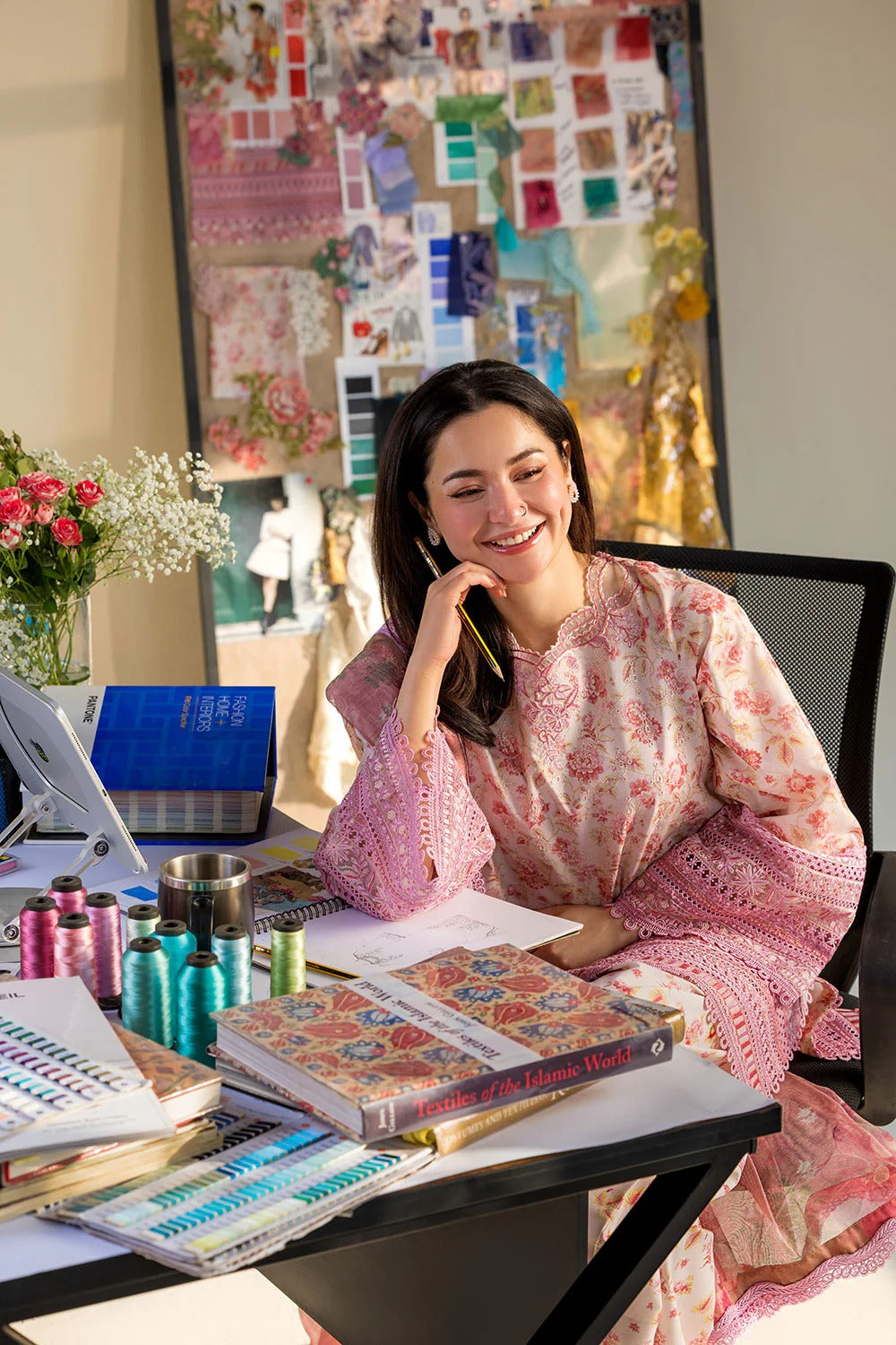 Woman sitting at a desk with stationery items, smiling on the phone.