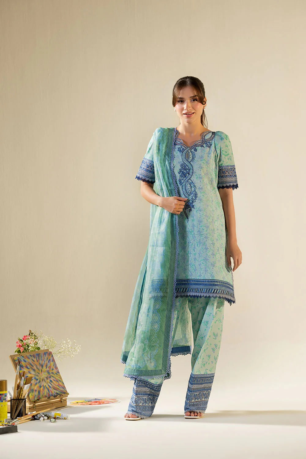 Woman wearing a blue and green traditional outfit with a beige background