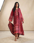 A woman models a traditional three-piece salwar kameez suit in deep red with intricate white and gold embroidery, featuring a matching embroidered dupatta, set against a neutral beige studio backdrop.