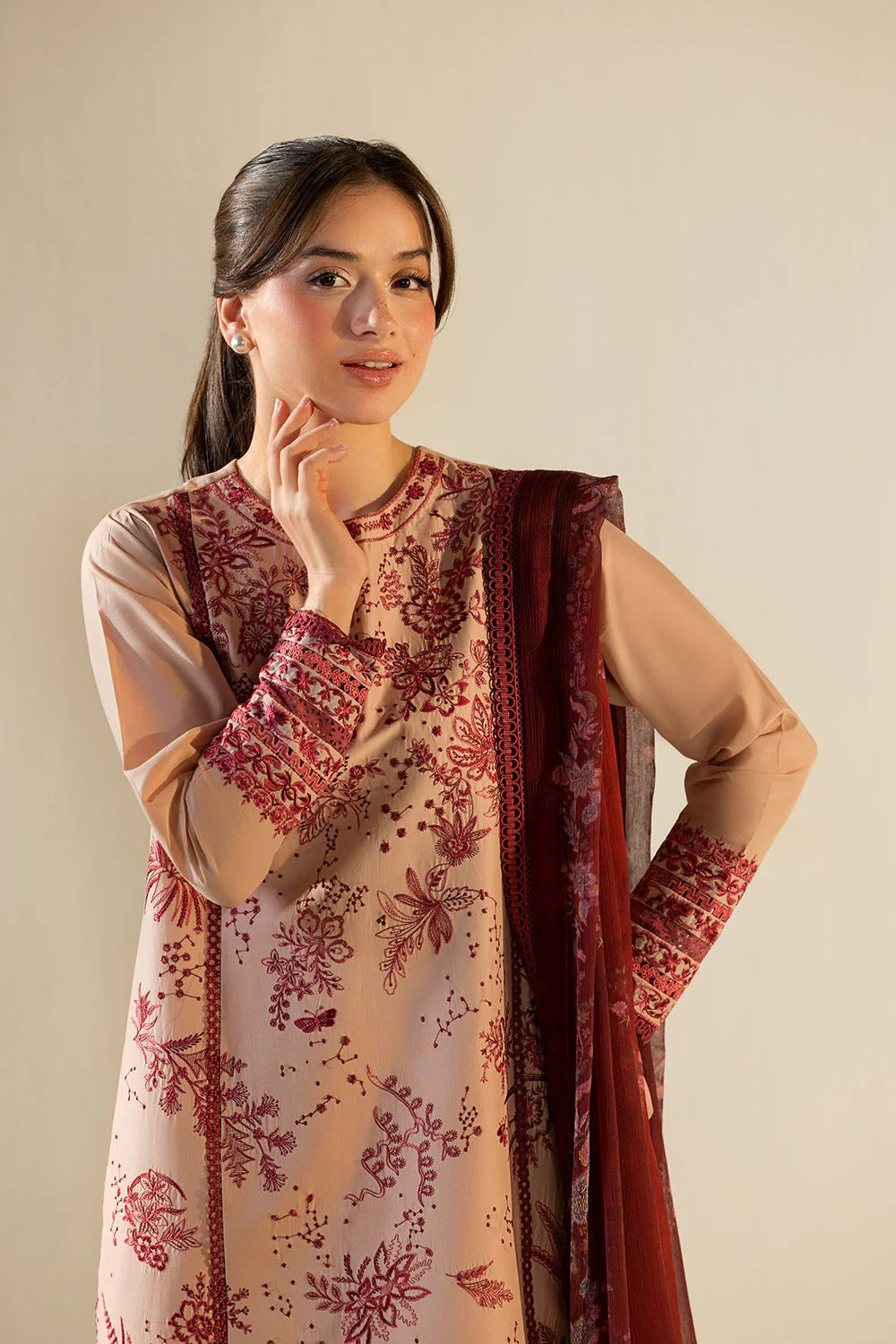 Woman wearing a traditional outfit with a floral pattern against a plain background