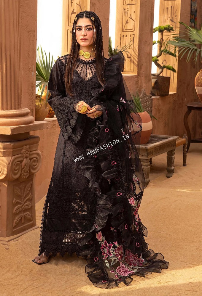 Woman in a black embroidered dress standing in an ornate room with columns and plants.