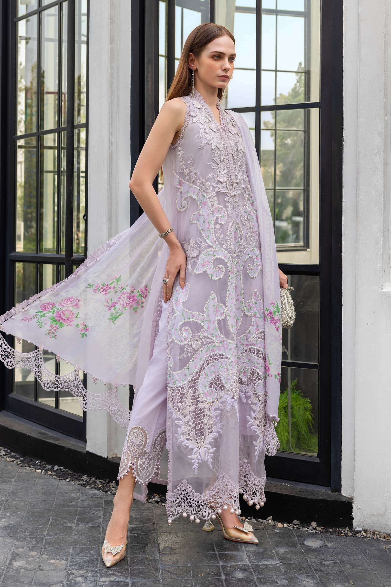 Woman wearing a light purple embroidered dress with floral details in an outdoor setting.