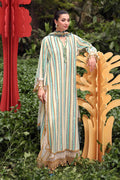 Woman in a long, striped dress standing in a garden with decorative elements.