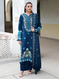 A woman modeling a dark teal blue traditional Indian salwar kameez suit with intricate light blue and white floral embroidery, standing in an outdoor architectural setting.