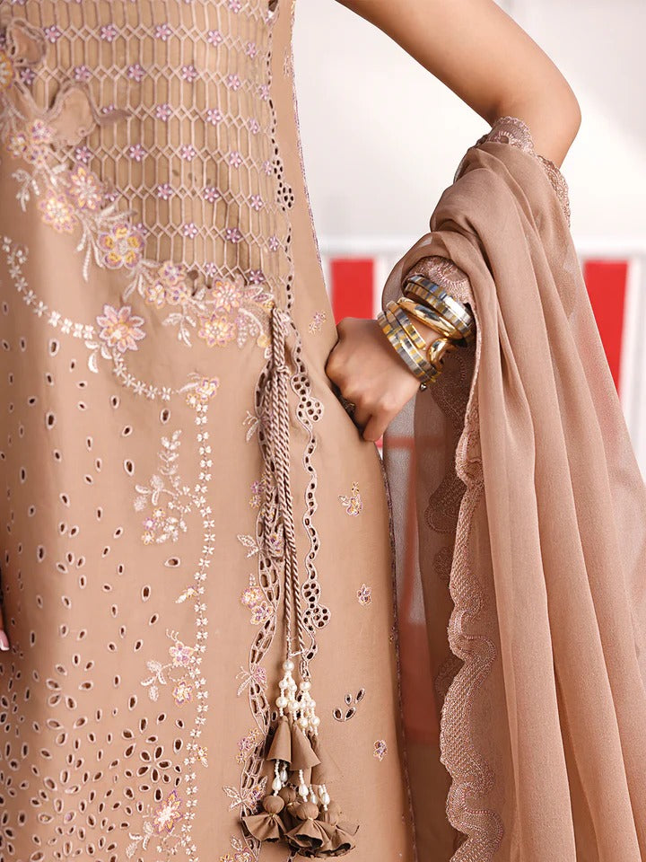 Close-up of a beige embroidered garment with tassels and a hand holding it.