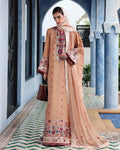 A woman models a peach-colored traditional South Asian salwar kameez suit with intricate floral embroidery and a matching dupatta, set against a blue archway corridor.