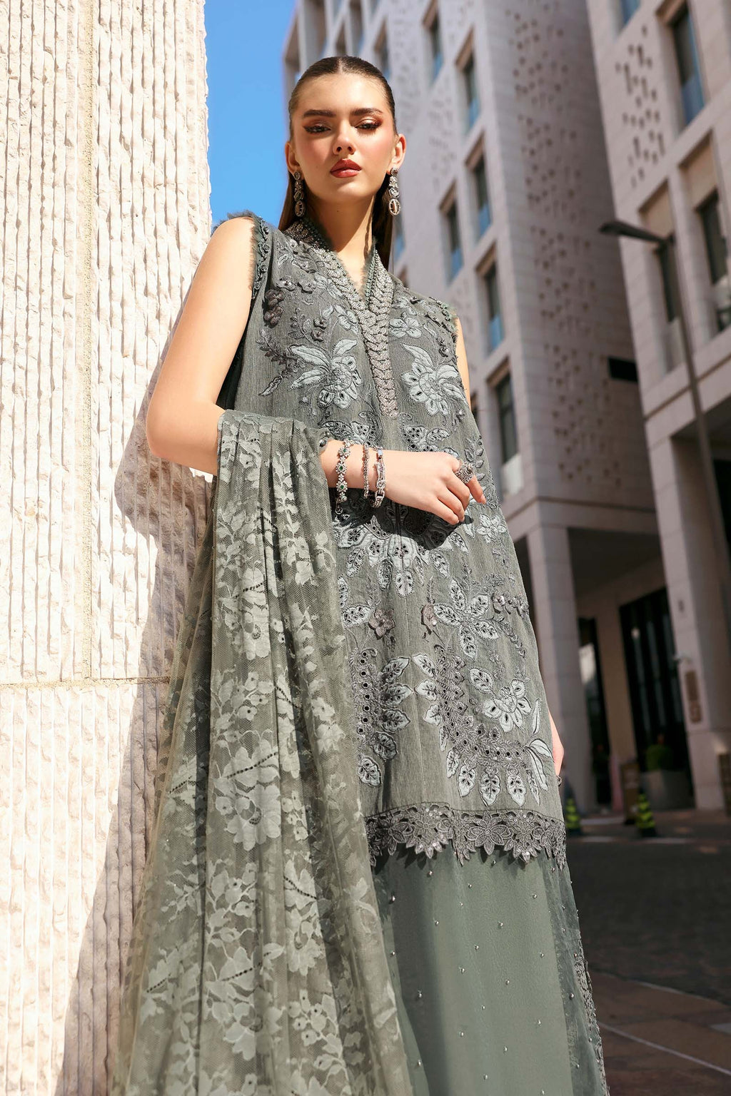 Woman wearing a gray embroidered outfit with a building in the background