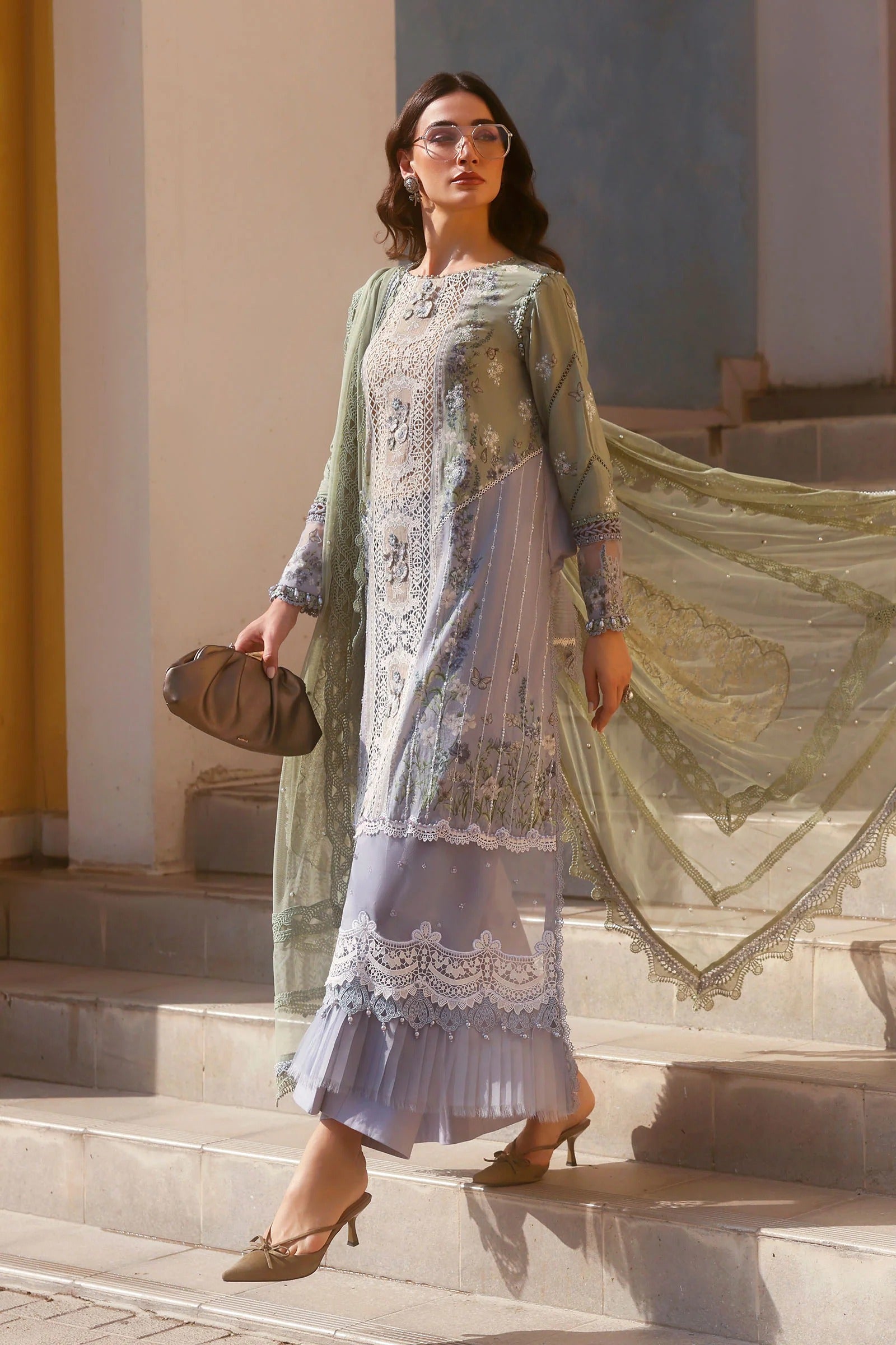 Woman in a light green and white traditional outfit with a matching dupatta, standing outdoors.