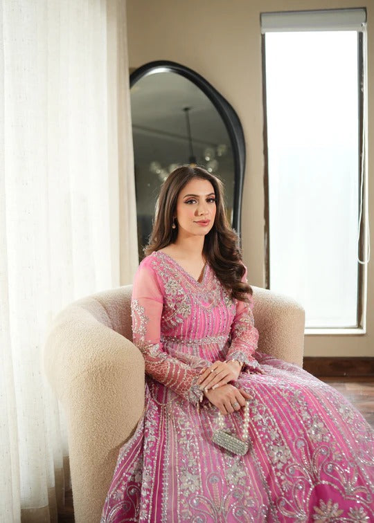 Woman in a pink traditional outfit sitting on a chair near a window.