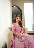 Woman in a pink traditional outfit sitting on a chair near a window.
