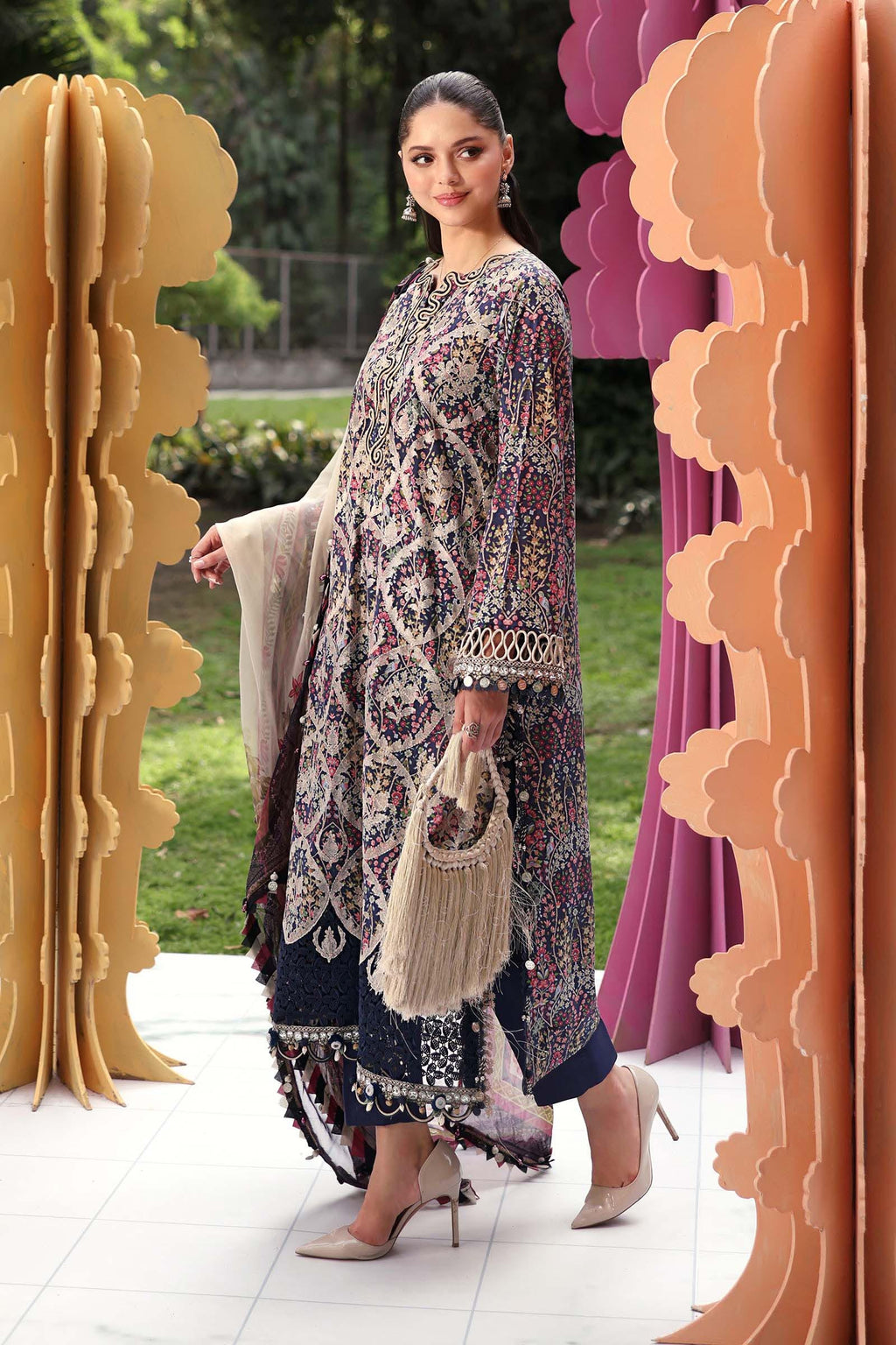 Woman in a floral dress standing in front of decorative arches with a garden background