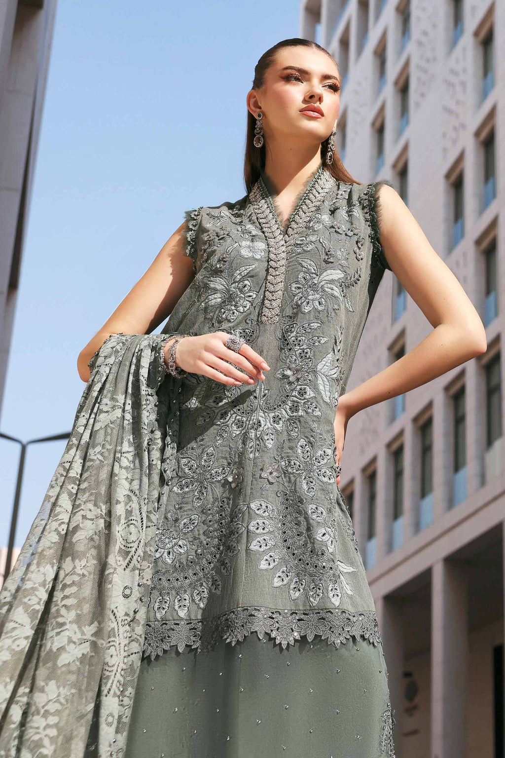 Woman wearing a gray embroidered outfit with a building in the background
