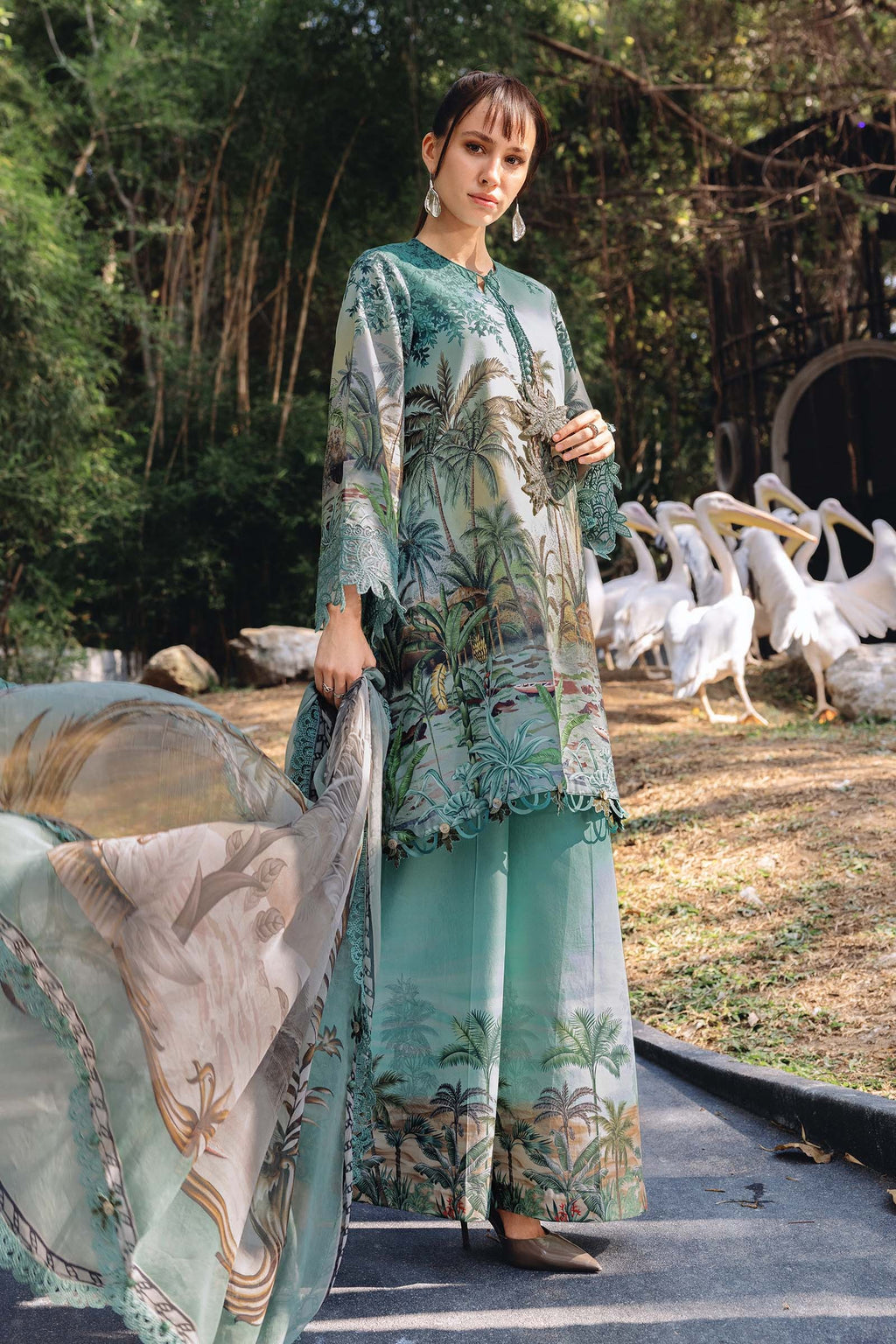 Woman in a floral outfit standing in front of a group of pelicans.