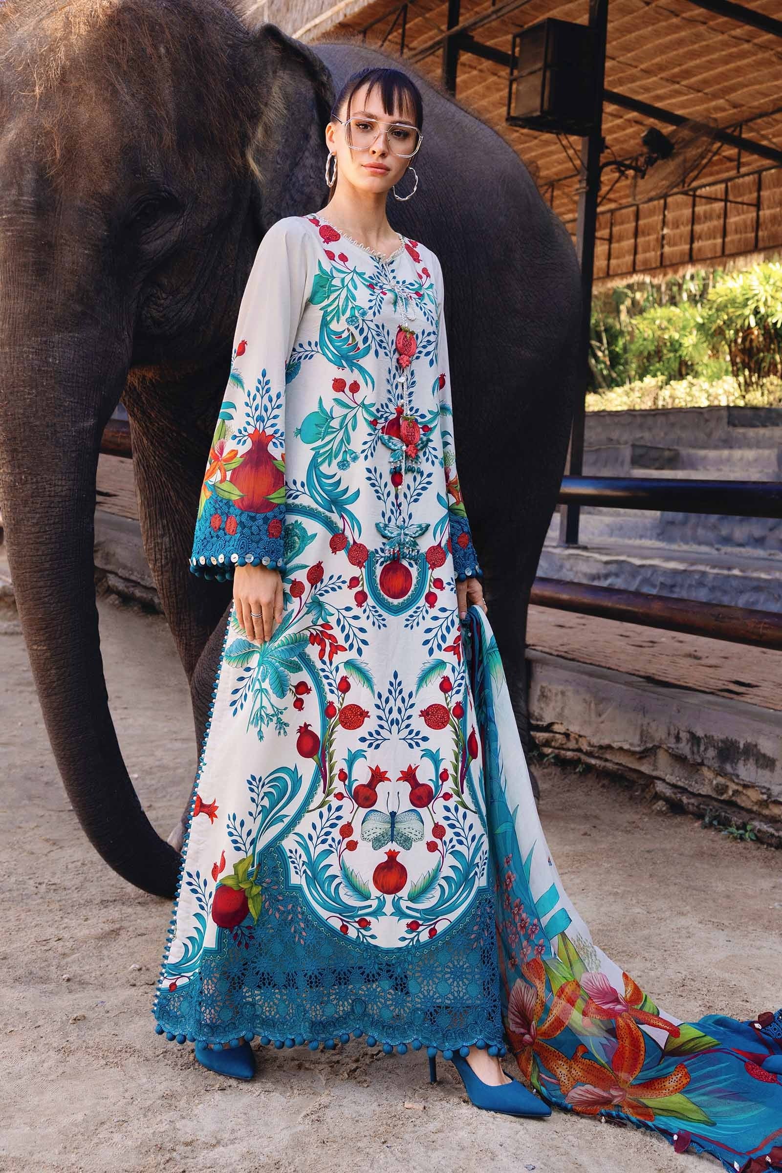 Woman in a colorful embroidered dress standing next to an elephant