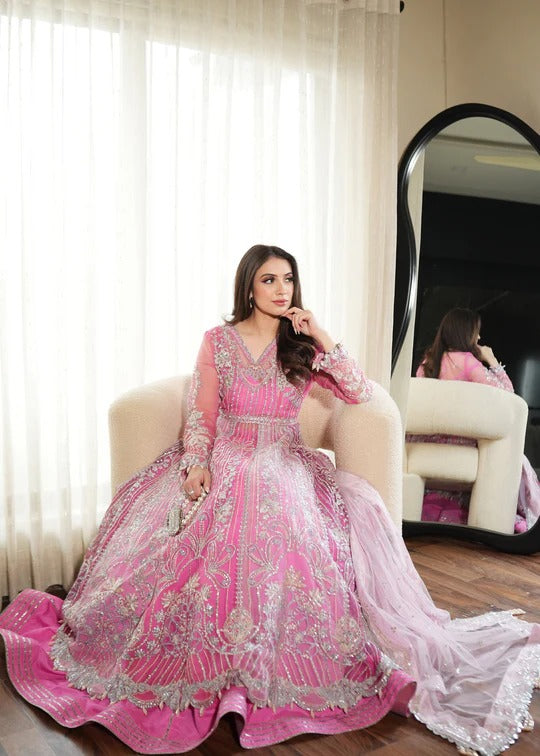 Woman in a pink and white traditional outfit sitting on a chair.