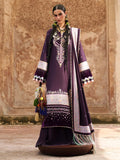 A woman models a traditional South Asian outfit consisting of a deep purple kurta with intricate silver and white embroidery, a matching purple dupatta with silver borders, and a brown embroidered tassel accessory, set against a textured stone wall background.