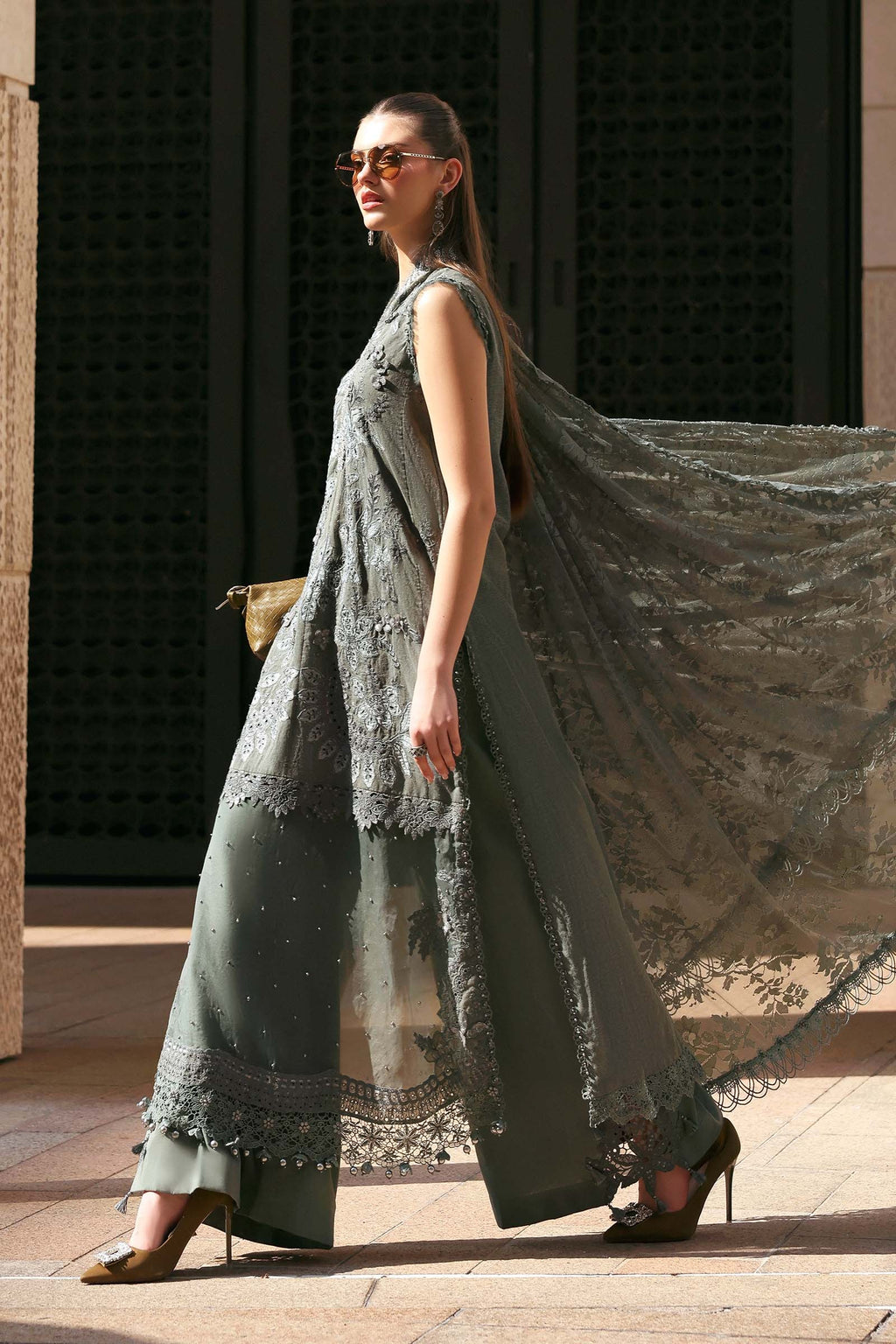 Woman wearing a long, flowing green dress with lace details on a city street.