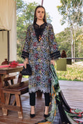 Woman in a floral dress standing outdoors with a wooden table and greenery in the background