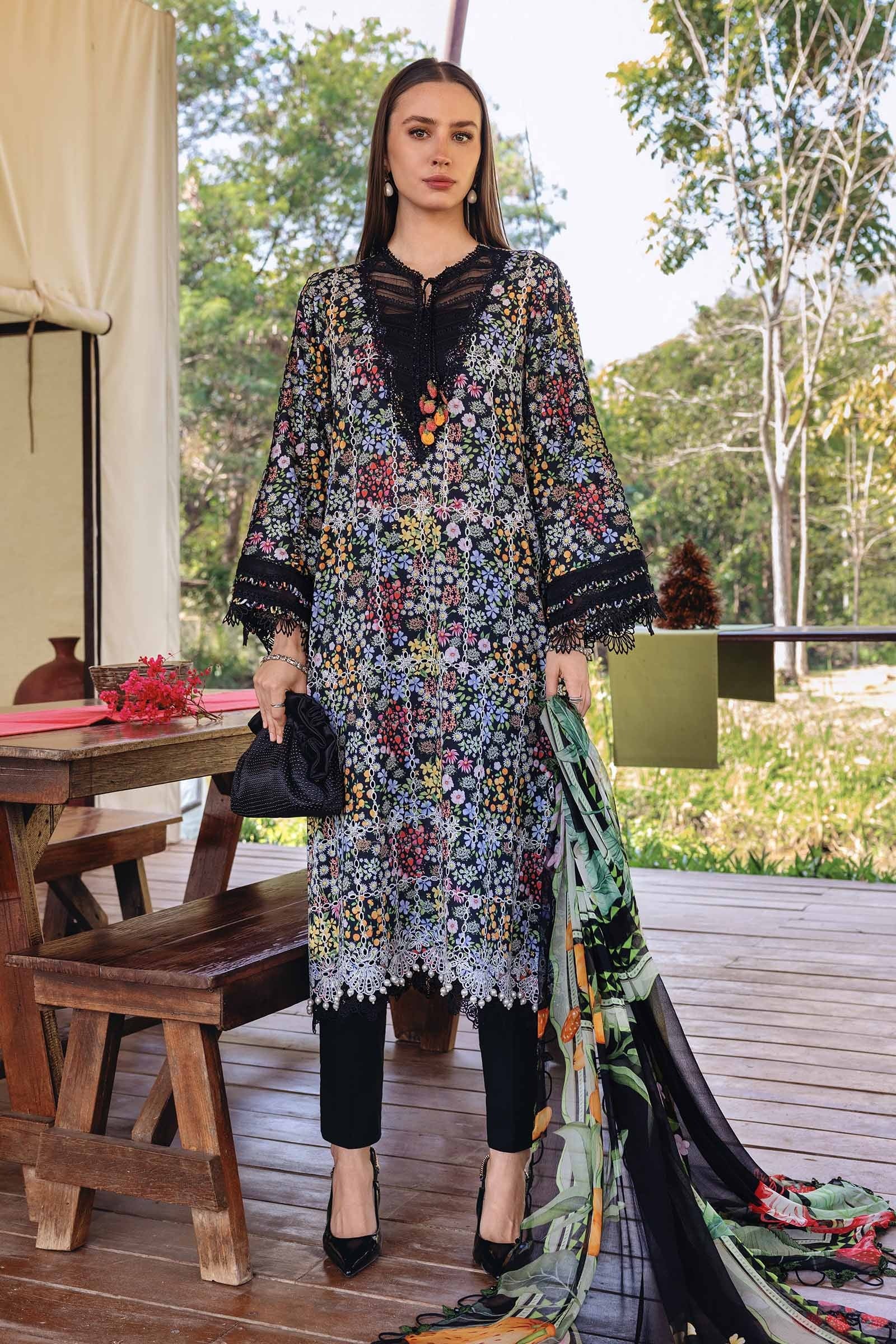 Woman in a floral dress standing outdoors with a wooden table and greenery in the background