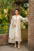 Woman in a traditional embroidered outfit standing outdoors near a brick wall.