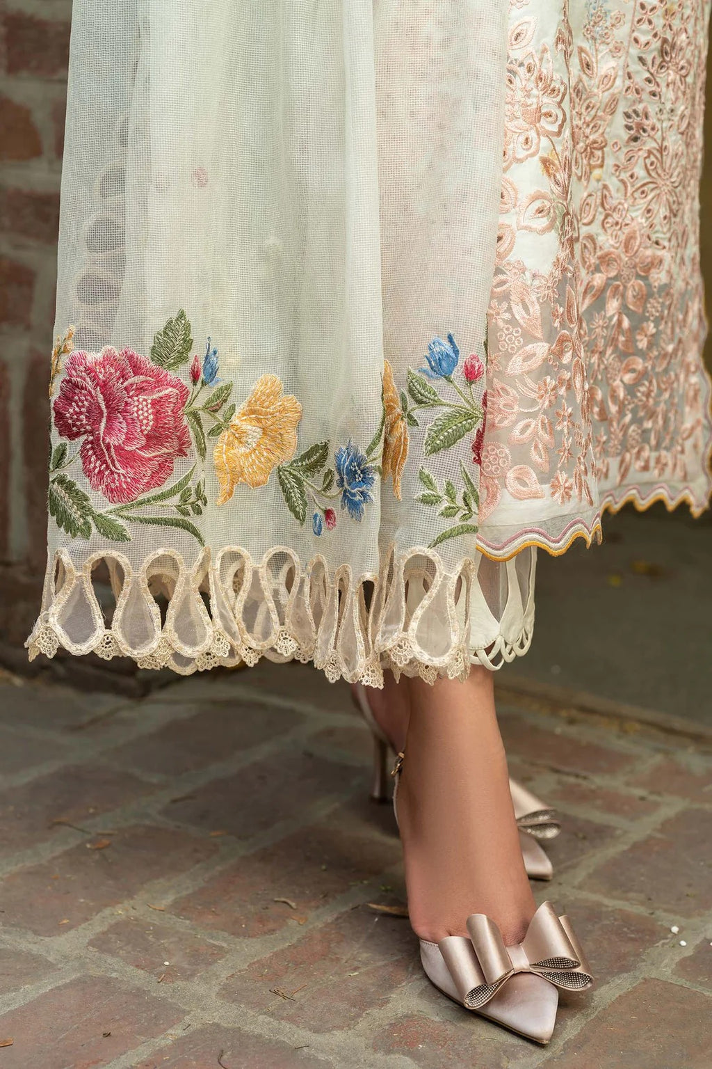 Embroidered lace skirt with floral patterns and high-heeled shoes on a stone floor.