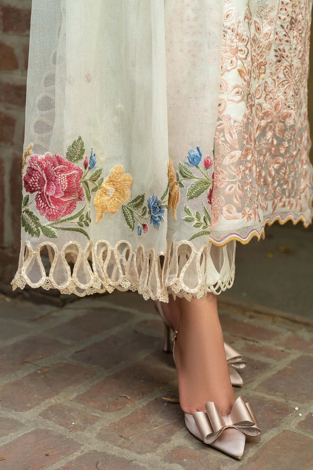 Embroidered lace skirt with floral patterns and high-heeled shoes on a stone floor.